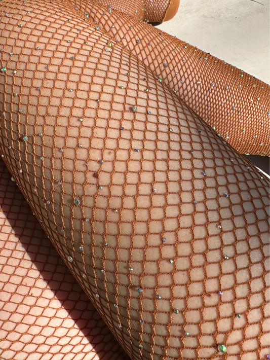 Close-up of fishnet stockings with rhinestones on a concrete surface.